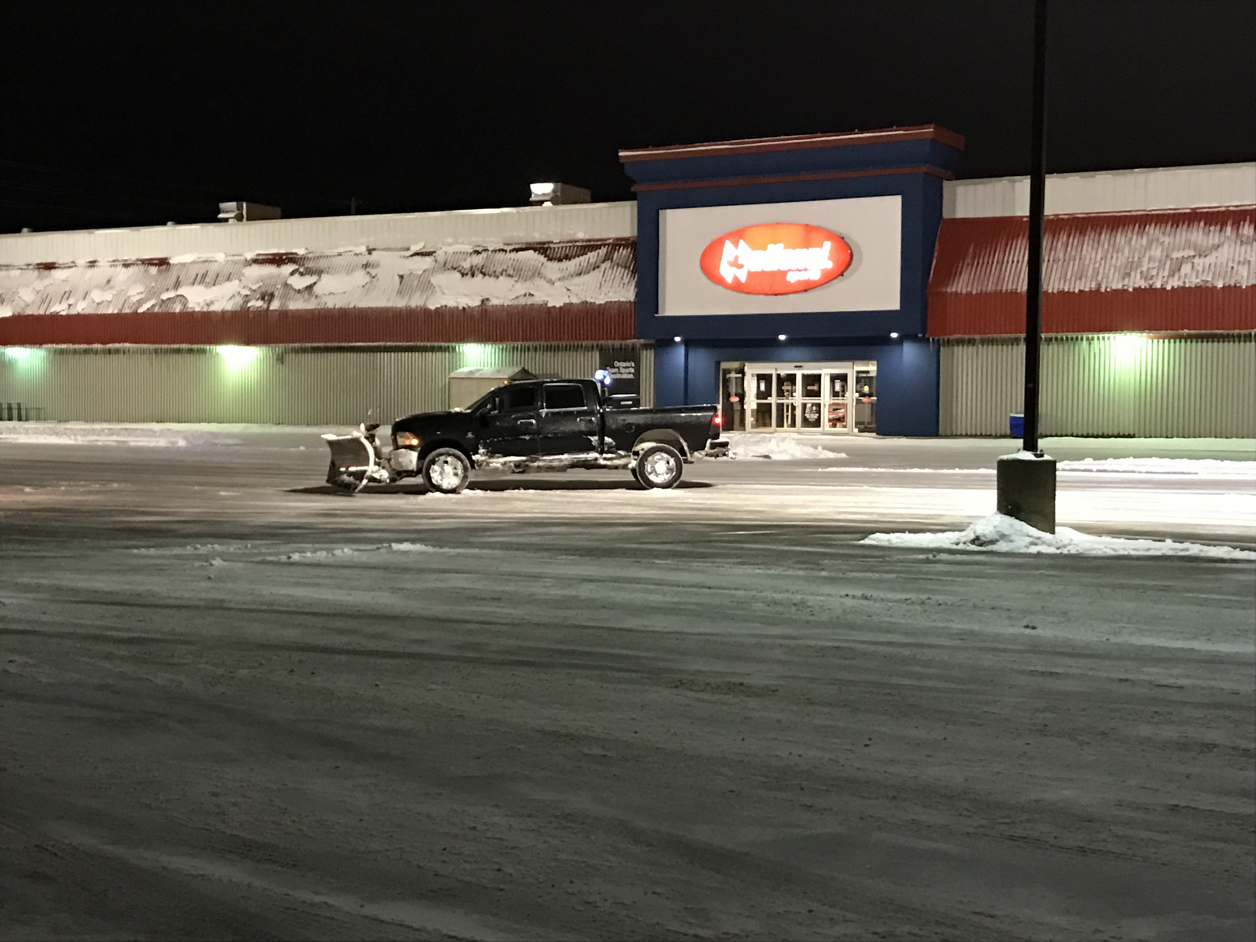 Phil's snowplow truck at a commercial property at night